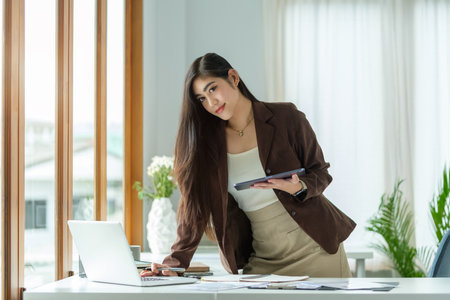 Successful millennial female entrepreneur standing at modern workplace.の写真素材