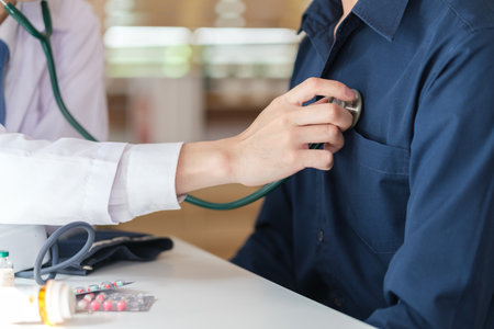 Caring doctor using stethoscope listening to patient heart, checkup examination in clinic.の写真素材