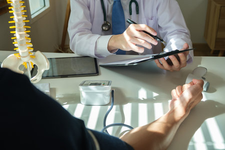 Orthopedist pointing at digital tablet, explaining treatment course, giving recovery advice to male patient. Medical, orthopedic and health care concept.の写真素材