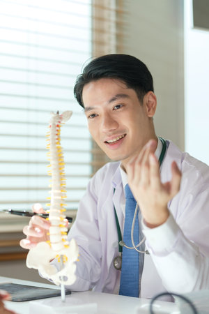 Male orthopedic surgeon showing artificial spine, explaining treatment course, giving recovery advice to patient. Medical, orthopedic and health care concept.の写真素材