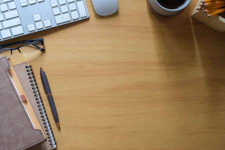 Simple workplace with keyboard, glasses, notebook and cup of coffee on wooden desk. Top view with space for your text.の写真素材