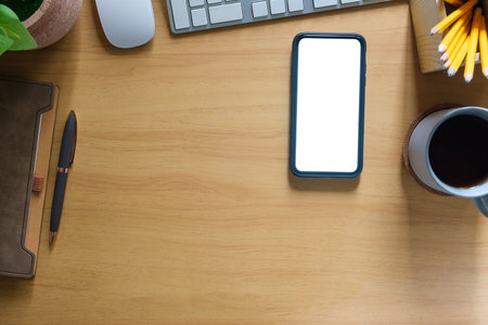Top view smartphone with blank screen, notebook and coffee cup on wooden table.の写真素材