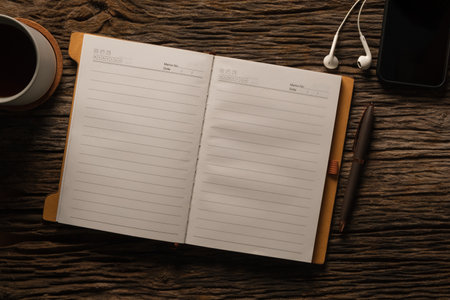 Open notepad, pen, glasses and cup of coffee on wooden desk. Top view with space for your text.の写真素材