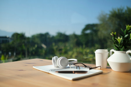 Laptop computer with blank display, potted plant, picture frame and stationery on white table.の写真素材
