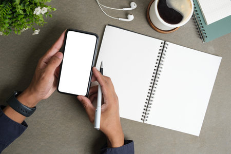Above view of man using mobile phone at creative workspace. Blank screen for your advertise design.の写真素材
