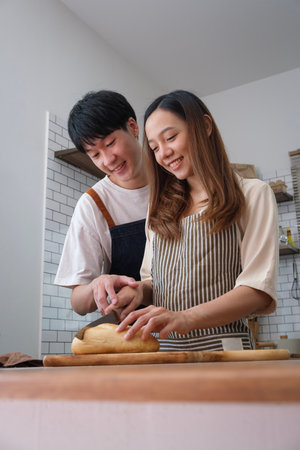 Beautiful young couple preparing meal, making fresh dough for breakfast in the kitchen.