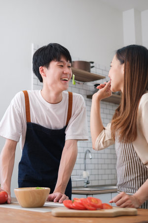 Happy young couple cooking together in the kitchen and enjoy spending time on weekend at home.の写真素材