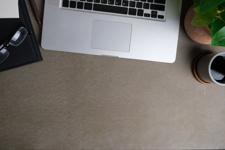 Laptop computer, coffee cup, books and houseplant on grey table. Stylish workspace, Top view with...