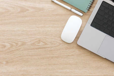 Top view laptop, notepad and cup of coffee on wooden table with copy space for text.