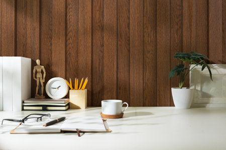 Comfortable workplace with notebook, glasses, coffee cup and picture frame on white table.の写真素材