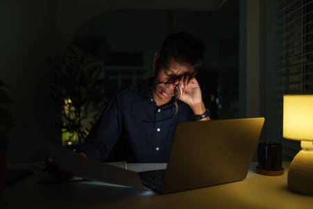 Tired young businessman working in office at night. Overworking concept.の写真素材