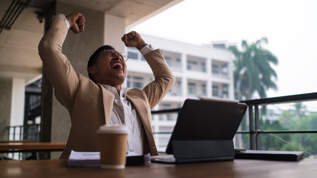 Happy adult businessman celebrating success, raising hands up and screaming.の写真素材