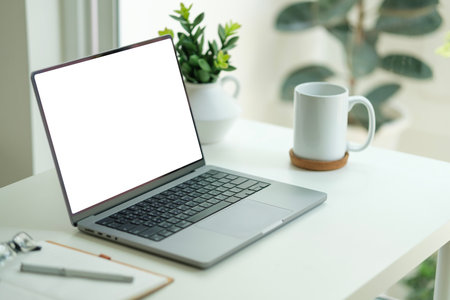 Laptop with blank display, glasses, notebook and houseplant on wooden table near glass window.の写真素材