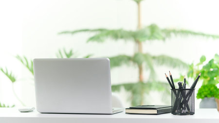 Laptop computer on white table near window with view of garden.の写真素材