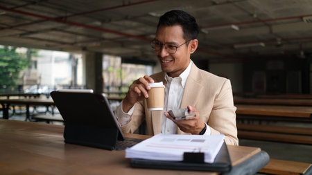 Smiling millennial businessman using digital tablet and working with financial reports.の写真素材