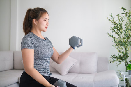 Sporty young woman exercising at home with dumbbells.の写真素材