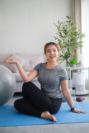 Attractive woman practicing yoga, doing Half lord of the fishes on mat at home. Healthy lifestyle concept.の写真素材