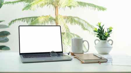 Laptop, coffee cup and notebook on white table. Empty screen for your advertise design.の写真素材