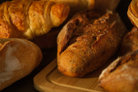 Fresh loaf of rustic traditional bread with wheat grain ear on wooden table.の写真素材