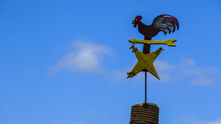 Hen-shaped weather vane on blue sky background.の写真素材