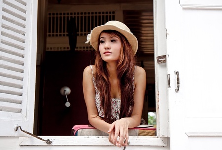 Beautiful asian woman looking out of the window in modern vintage conceptの写真素材