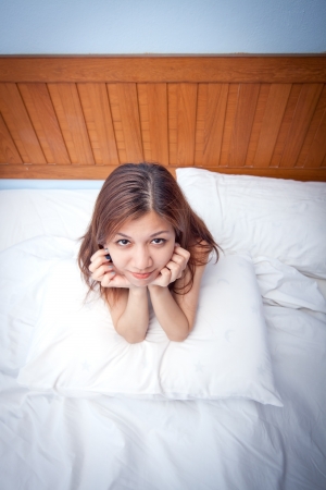 Beautiful young Asian woman relaxing on the bedの写真素材