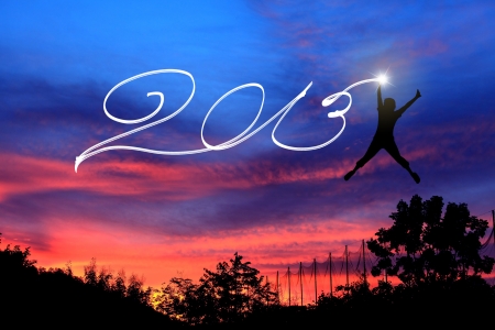 Young man jumping and drawing 2013 before sunrise skyの写真素材