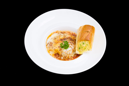 a plate of lasagna with hot garlic breadの写真素材