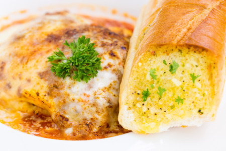 a plate of lasagna with hot garlic breadの写真素材