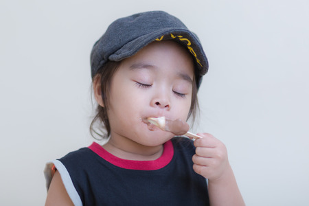 Little girl eating ice-cream indoors at her houseの写真素材
