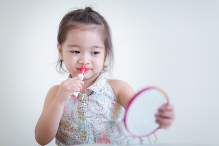Little girl with mirror doing makeup at her houseの写真素材