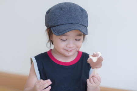 Little girl eating ice-cream indoors at her houseの写真素材