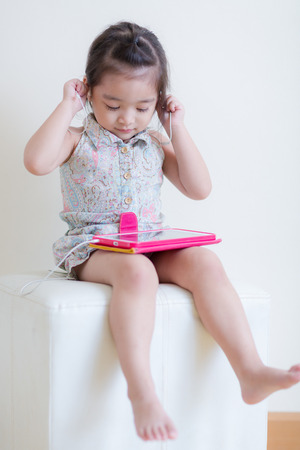 Little Girl playing Tablet Computer at her houseの写真素材