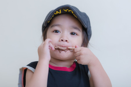Little girl eating ice-cream indoors at her houseの写真素材