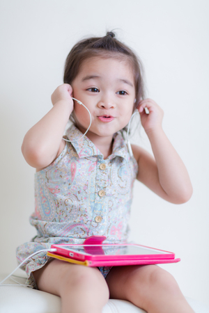 Little Girl playing Tablet Computer at her houseの写真素材