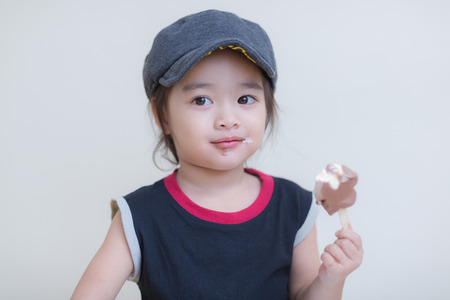 Little girl eating ice-cream indoors at her houseの写真素材
