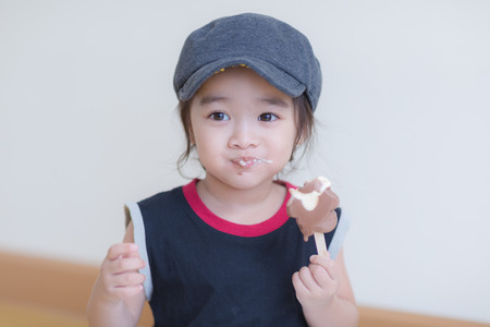 Little girl eating ice-cream indoors at her houseの写真素材