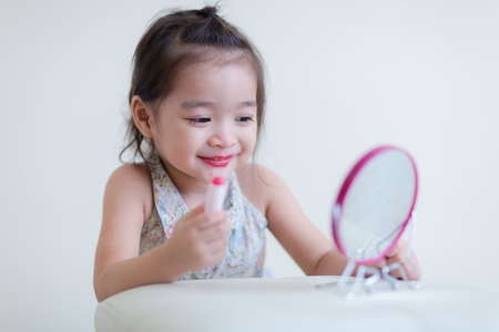 Little girl with mirror doing makeup at her houseの写真素材