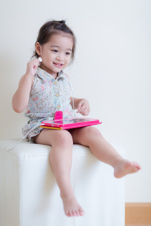 Little Girl playing Tablet Computer at her houseの写真素材