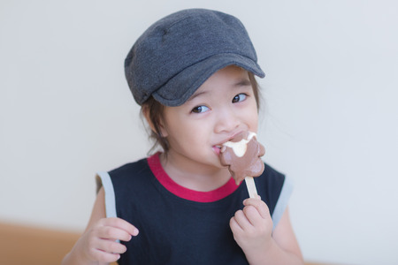 Little girl eating ice-cream indoors at her houseの写真素材