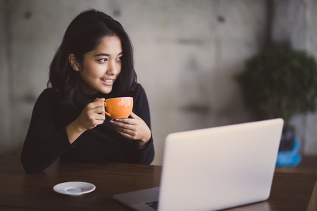 Asian  woman working with her laptop and coffee on desk, Vintage colorの写真素材