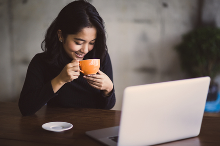 Asian  woman working with her laptop and coffee on desk, Vintage colorの写真素材