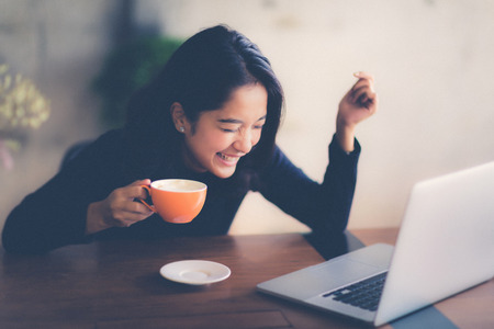 Asian  woman working with her laptop and coffee on desk, Vintage colorの写真素材