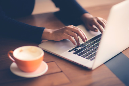 Hand of woman working with her Laptop and Coffee by the sideの写真素材