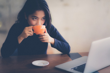 Asian  woman working with her laptop and coffee on desk, Vintage colorの写真素材