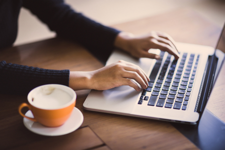 Hand of woman working with her Laptop and Coffee by the sideの写真素材