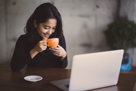 Asian  woman working with her laptop and coffee on desk, Vintage colorの写真素材