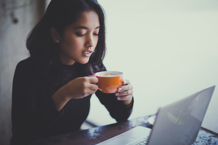 Asian  woman working with her laptop and coffee on desk, Vintage colorの写真素材