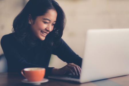 Asian  woman working with her laptop and coffee on desk, Vintage colorの写真素材