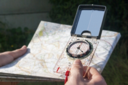 Compass hand held over blurred map as if taking a bearing